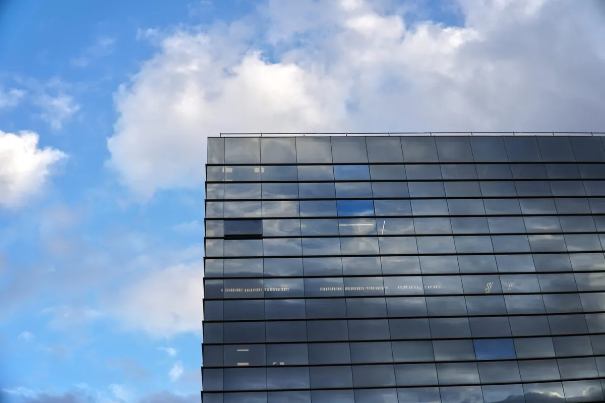 Modern glass office tower against a blue sky
